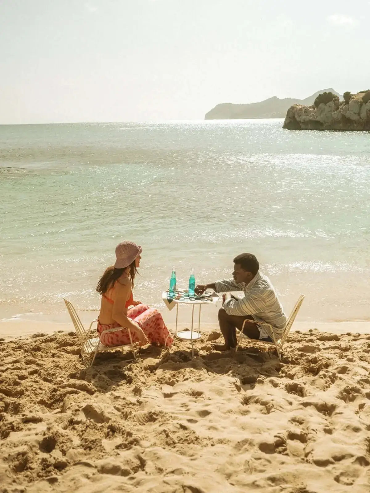Ein Mann und eine Frau sitzen am Strand und stoßen mit SALITOS Blue an