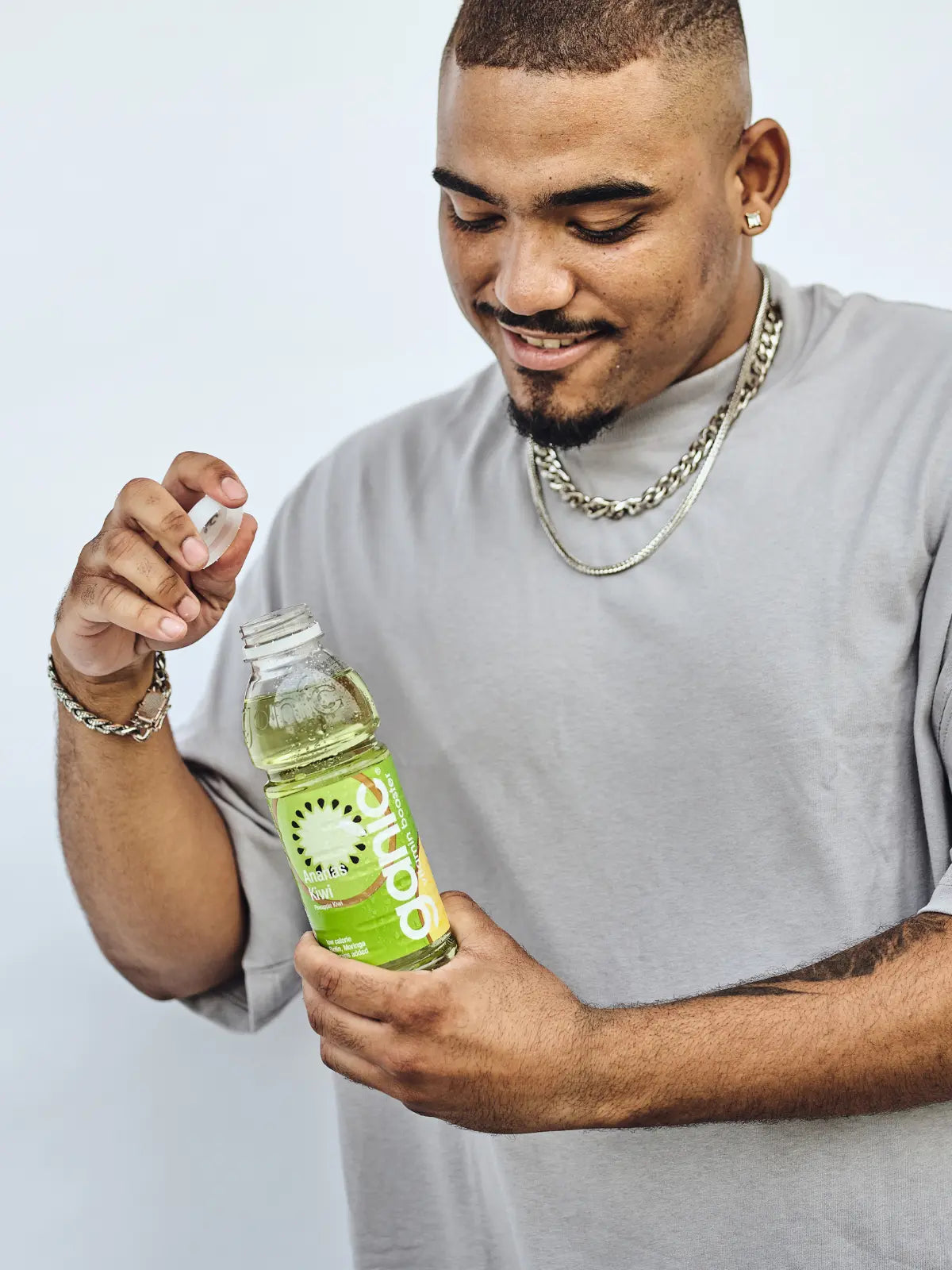 ein glücklicher mann hält eine flasche ganic ananas kiwi in der hand