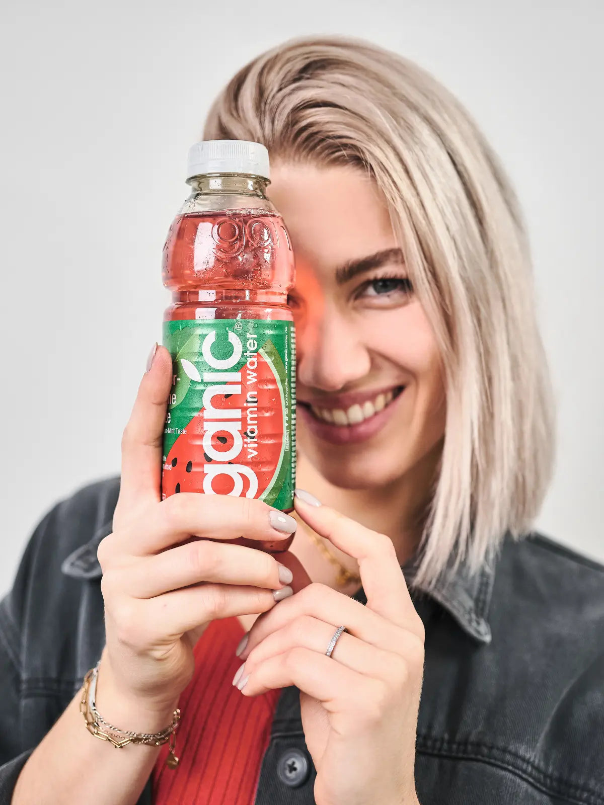 eine glückliche frau hält eine flasche ganic wassermelone minze