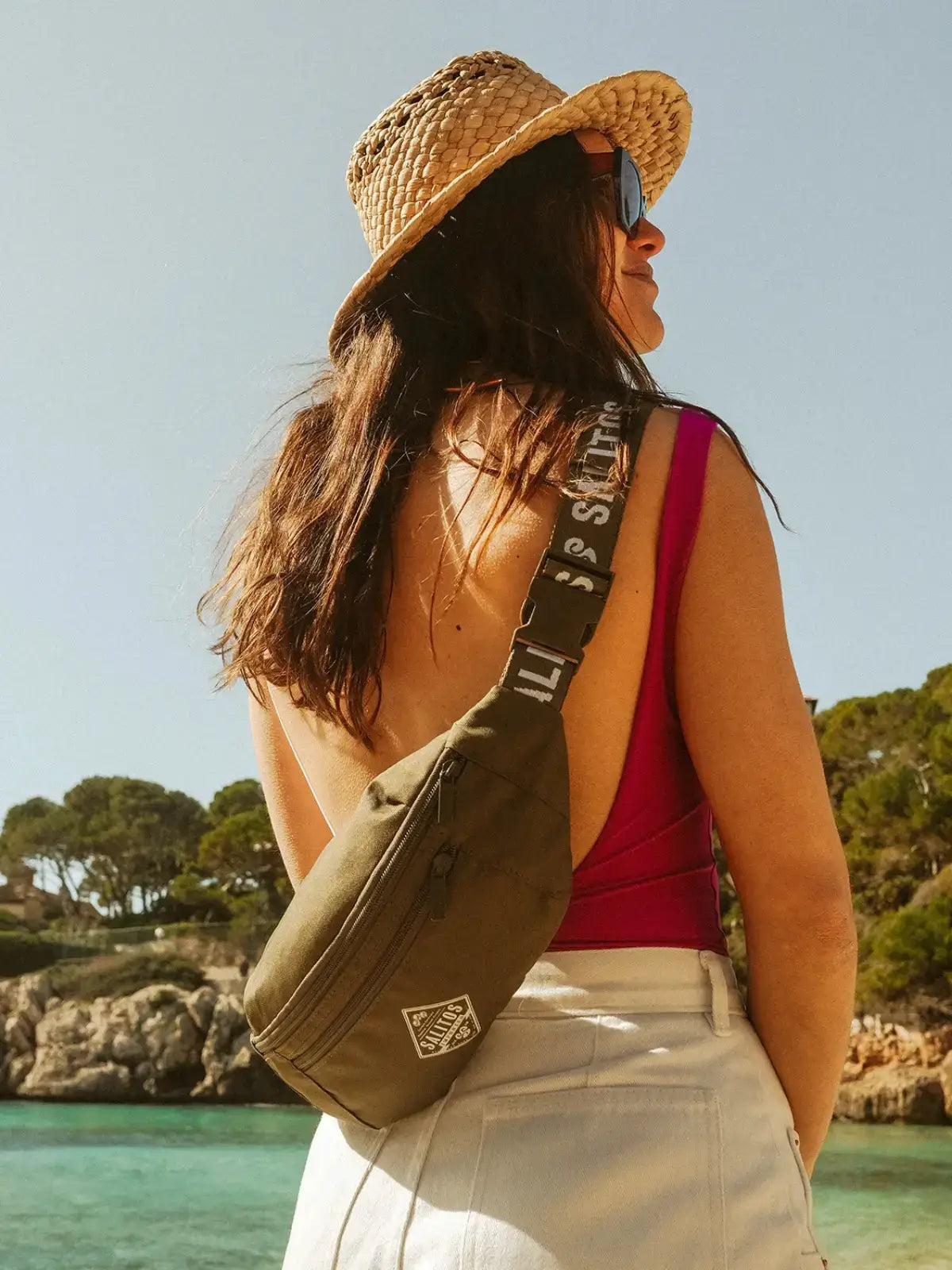 Eine Frau die am Strand steht und umgeben vom blauen Meer ist, trägt eine Tasche von SALITOS