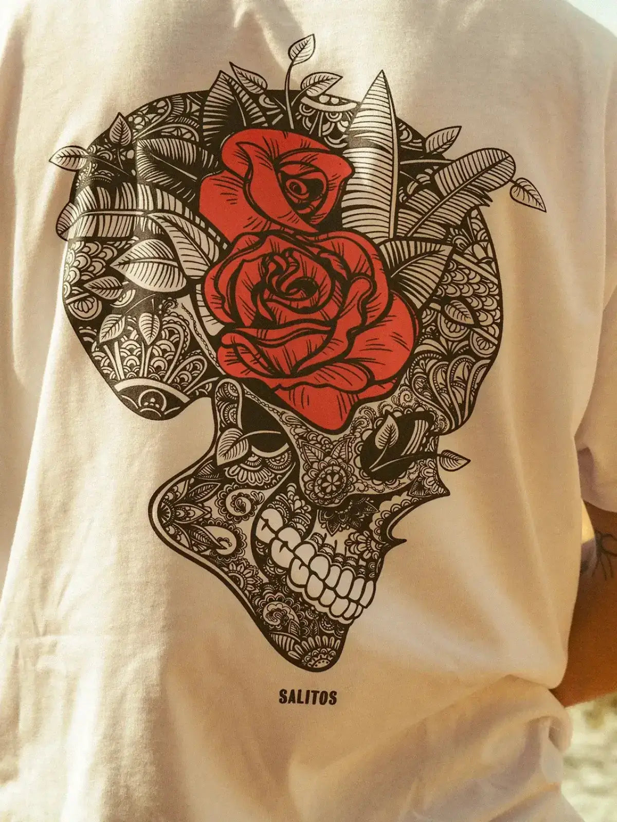 Ein Mann trägt ein weißes Salitos T-Shirt mit Totenkopf Druck auf dem Rücken