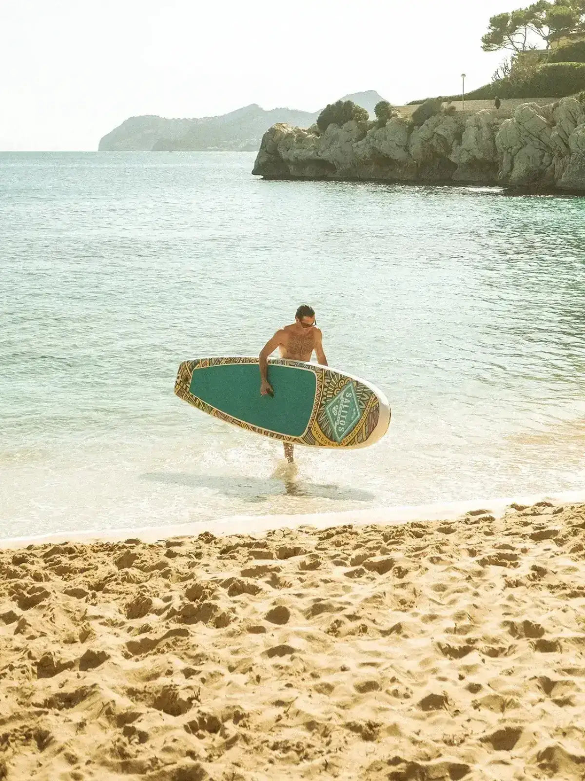 Ein Mann am Strand mit türkisen Salitos Stand up Board