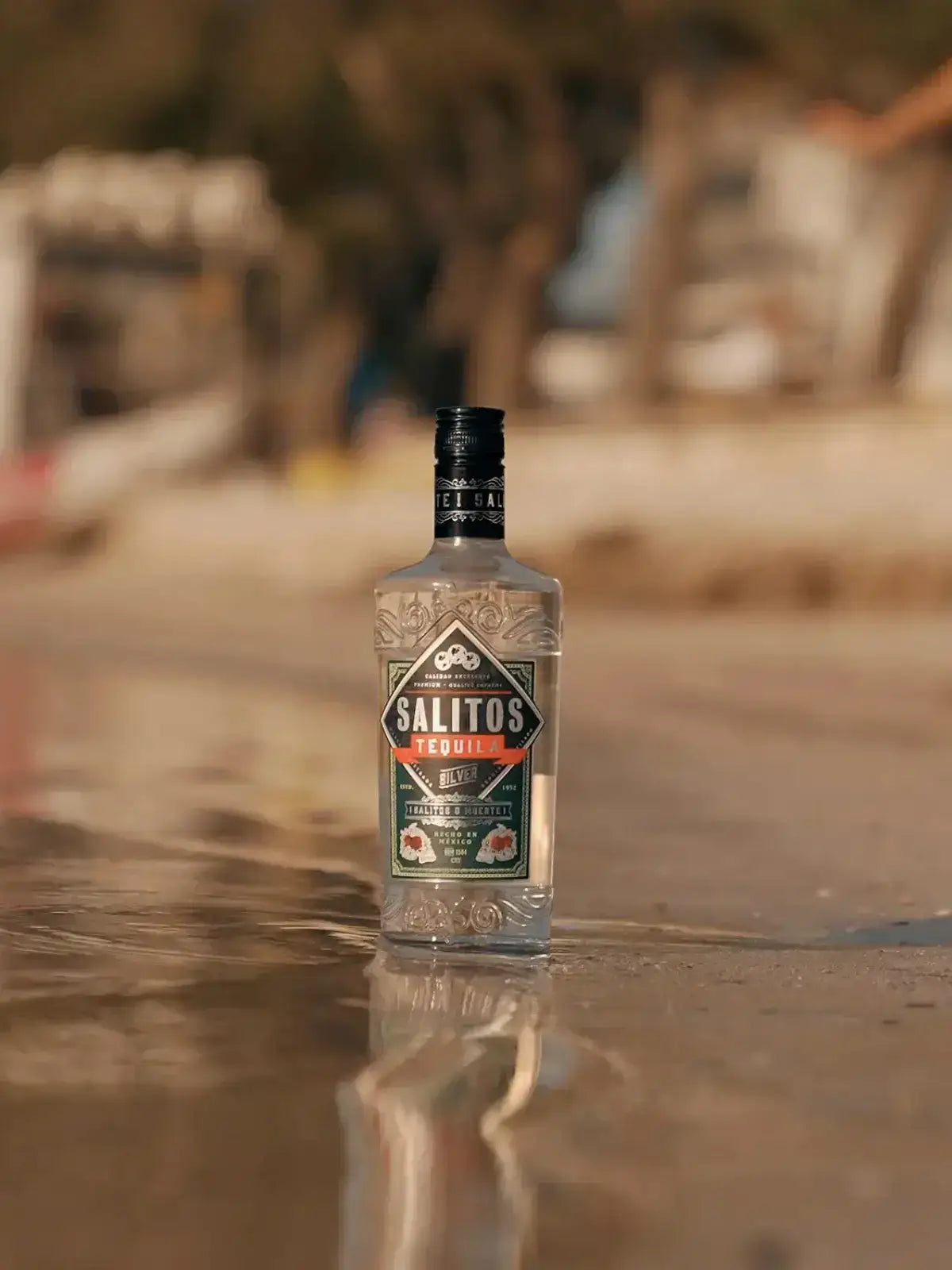 Eine Flasche SALITOS Tequila Silver steht im Wasser am Strand